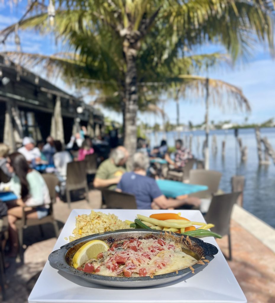 Waterfront meal at Yucatan Restaurant in Matlacha Florida with palm trees and water views.