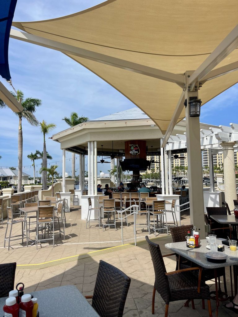 Outdoor seating at Tarpon Point Marina in Cape Coral looking toward The Nauti Mermaid near Marker 92 and The Westin Cape Coral