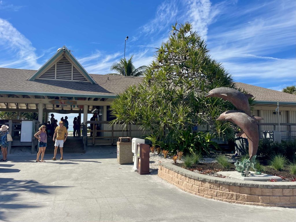 Entrance area at Lowdermilk Beach in Naples Florida with dolphin statue and beach pavilion