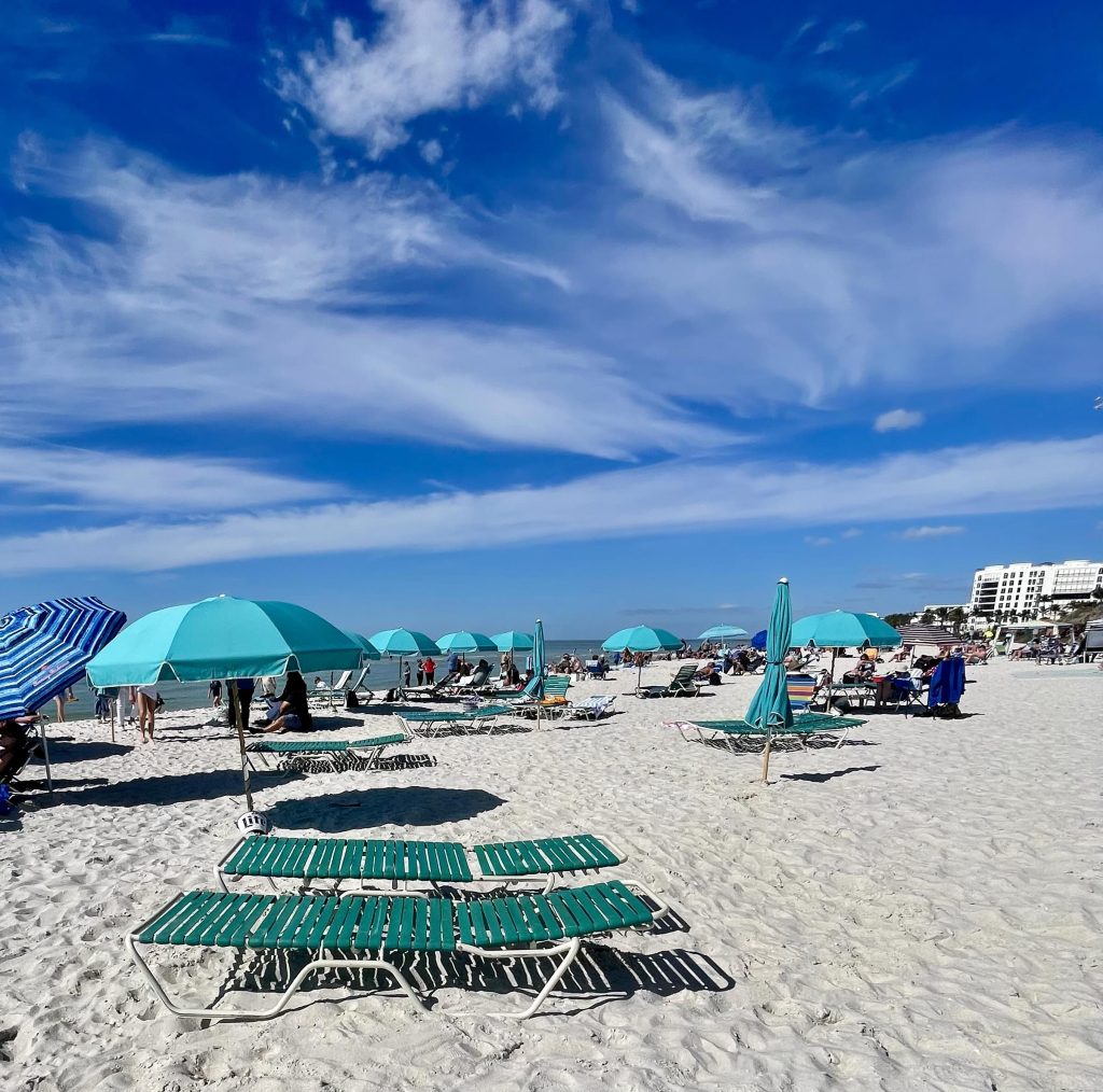 Beach chair and umbrella rentals set up on the sand at Lowdermilk Beach in Naples Florida