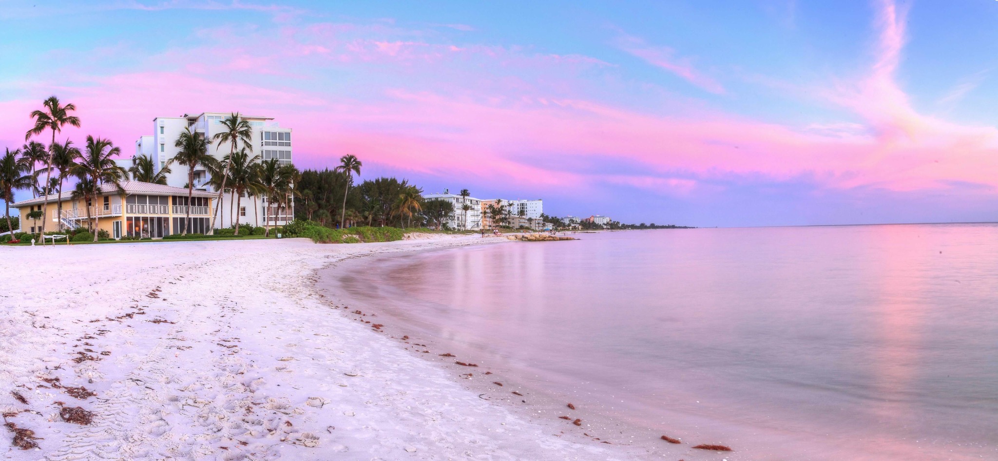 Lowdermilk Beach in Naples Florida at sunset with white sand, calm Gulf water and pastel pink sky