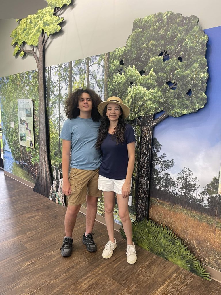 Mother and teen son standing in front of an indoor exhibit with tree displays at Busch Wildlife Sanctuary.