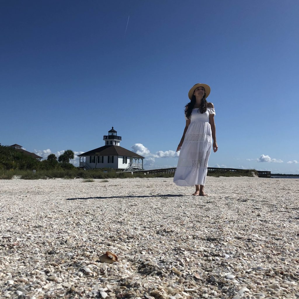 Woman standing on a shell-covered beach near the Port Boca Grande Lighthouse in Boca Grande, Florida