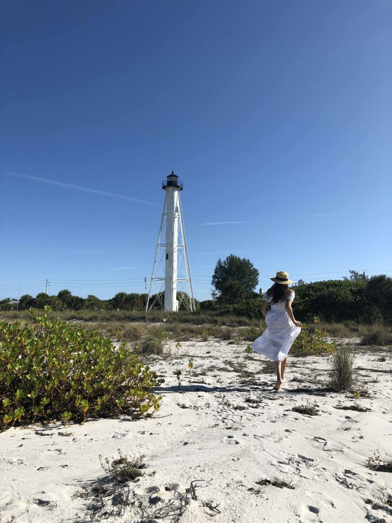 Woman walking toward the Gasparilla Island Lighthouse on the beach in Boca Grande, Florida