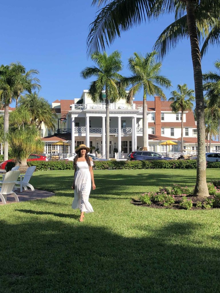 Woman standing in front of The Gasparilla Inn in Boca Grande, Florida, surrounded by palm trees