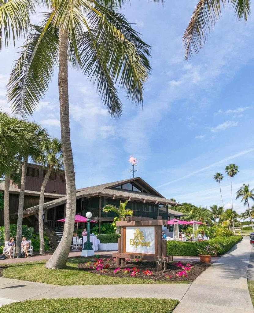 Exterior of The Pink Elephant restaurant in Boca Grande, Florida, with palm trees and pink umbrellas